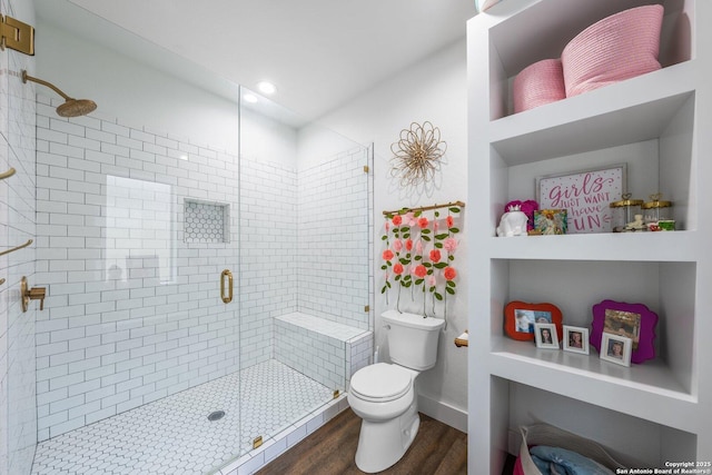 full bathroom with a stall shower, wood finished floors, toilet, and baseboards