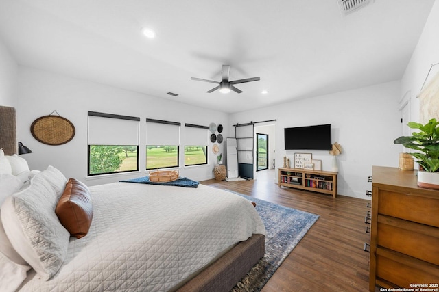 bedroom featuring a barn door, visible vents, wood finished floors, and recessed lighting