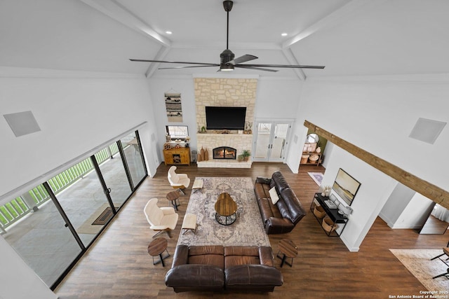 living area featuring a fireplace, ceiling fan, wood finished floors, high vaulted ceiling, and beamed ceiling