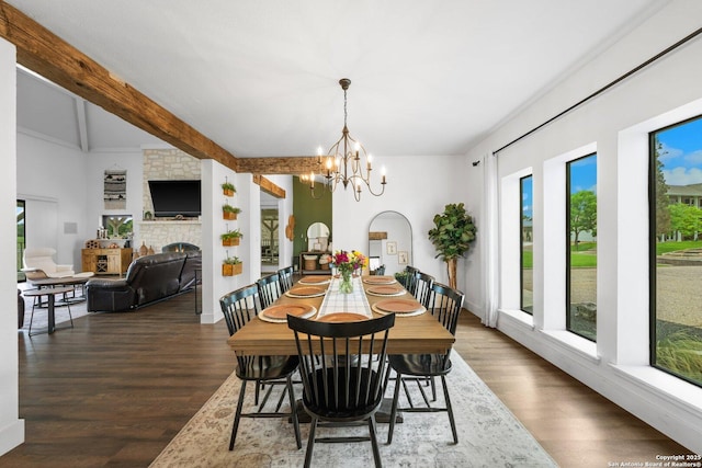 dining space featuring beamed ceiling, a fireplace, wood finished floors, and an inviting chandelier