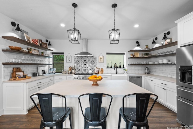 kitchen featuring appliances with stainless steel finishes, a sink, wall chimney exhaust hood, and open shelves