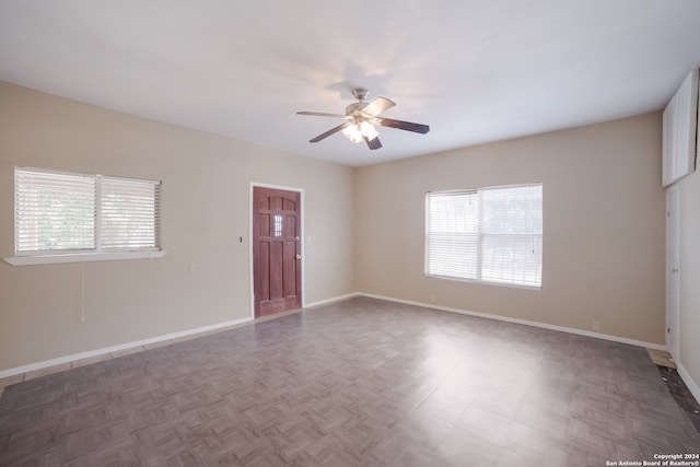 spare room featuring plenty of natural light, ceiling fan, and dark parquet floors