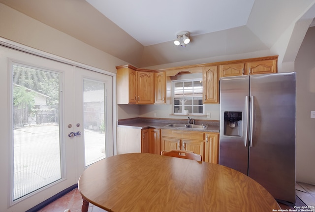 kitchen with light brown cabinets, sink, vaulted ceiling, stainless steel fridge, and light tile patterned floors