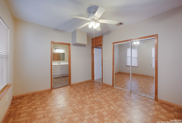 unfurnished bedroom with ceiling fan, sink, ensuite bathroom, and light parquet floors