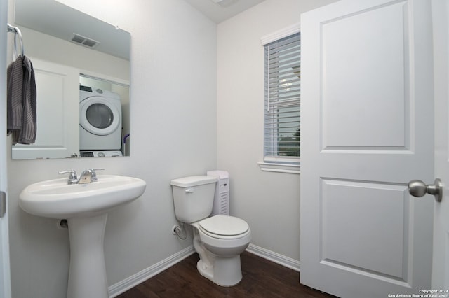 bathroom with hardwood / wood-style floors, stacked washer / drying machine, toilet, and sink