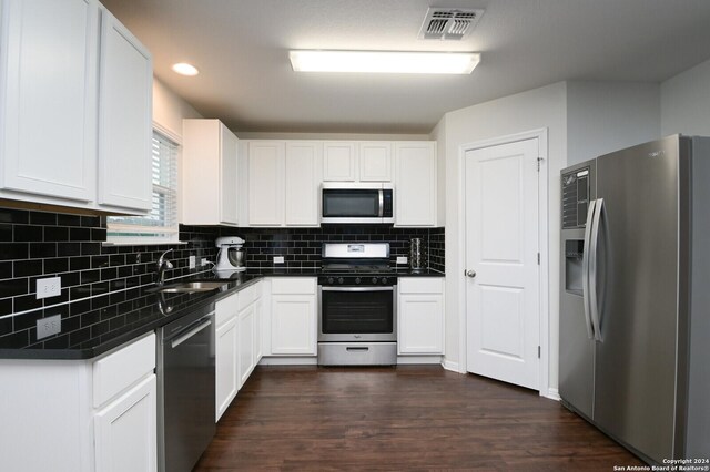 kitchen featuring sink, dark wood-type flooring, stainless steel appliances, tasteful backsplash, and white cabinets