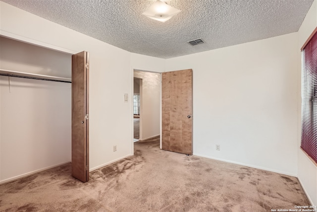 unfurnished bedroom featuring a closet, carpet floors, and a textured ceiling