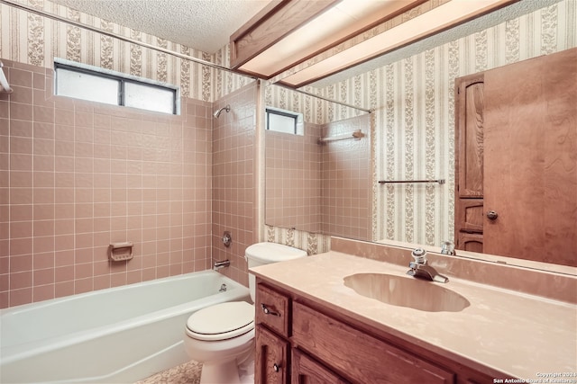 full bathroom featuring vanity, toilet, a textured ceiling, and tiled shower / bath