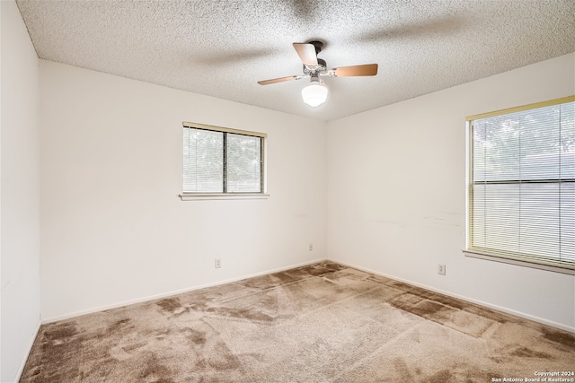 unfurnished room with ceiling fan, carpet floors, and a textured ceiling