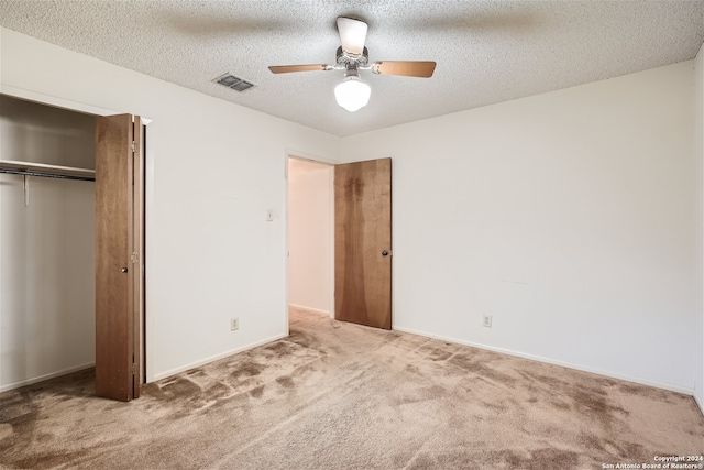 unfurnished bedroom with carpet, a textured ceiling, a closet, and ceiling fan