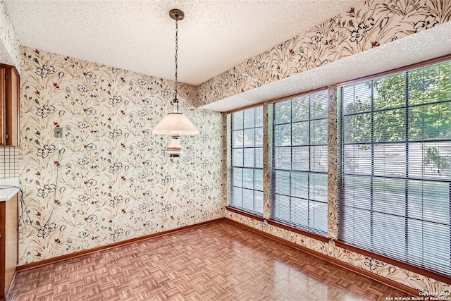 unfurnished dining area featuring parquet flooring and a textured ceiling