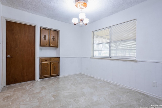 empty room with a textured ceiling and a chandelier