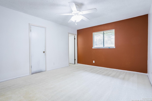 spare room featuring ceiling fan, light carpet, and a textured ceiling