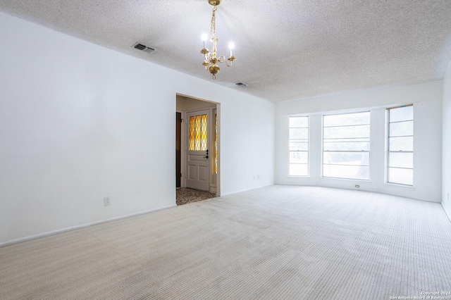 carpeted empty room with a chandelier and a textured ceiling