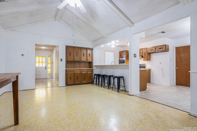 living room with a textured ceiling, lofted ceiling with beams, and ceiling fan