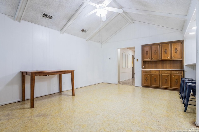 living room featuring vaulted ceiling with beams, ceiling fan, and a textured ceiling