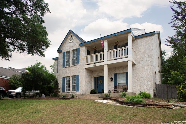 view of front facade with a balcony and a front lawn