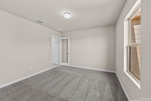 carpeted spare room featuring visible vents and baseboards