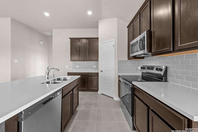 kitchen featuring light tile patterned flooring, a sink, light countertops, dark brown cabinets, and appliances with stainless steel finishes