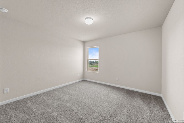 carpeted empty room with baseboards and a textured ceiling