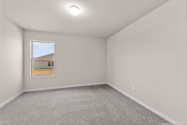 spare room featuring a textured ceiling, baseboards, and carpet floors