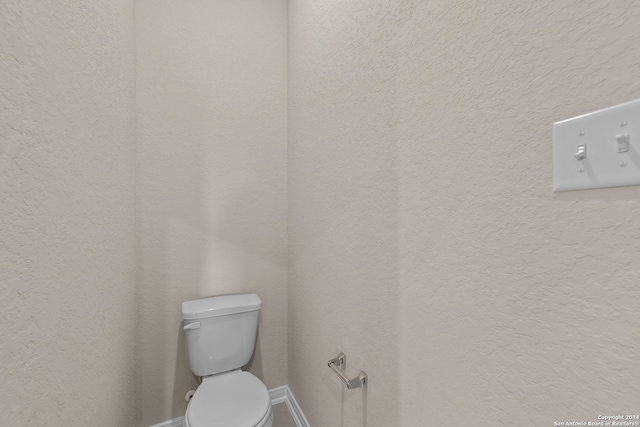 bathroom featuring toilet and a textured wall