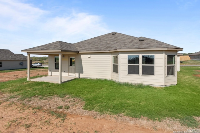 back of property with a patio, a lawn, and roof with shingles