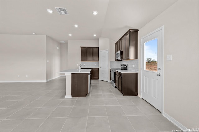 kitchen featuring tasteful backsplash, visible vents, open floor plan, a center island with sink, and appliances with stainless steel finishes