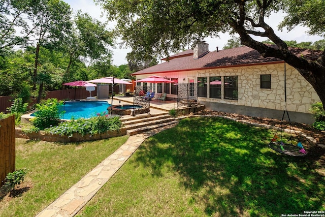 rear view of house with a lawn, a swimming pool with hot tub, and a patio