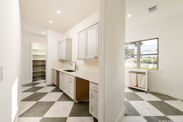 interior space featuring sink, white cabinetry, and backsplash