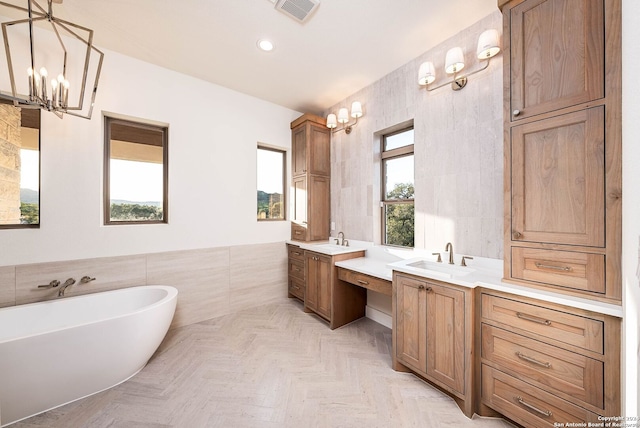 bathroom featuring a chandelier, tile walls, parquet floors, a bath, and vanity