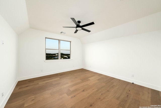 spare room with hardwood / wood-style floors, vaulted ceiling, and ceiling fan