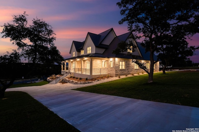 property exterior at dusk featuring a yard and covered porch