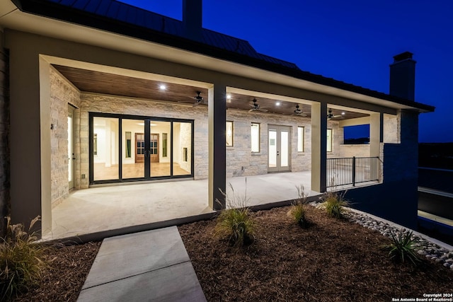 back house at night with a patio, french doors, and ceiling fan