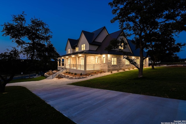 property exterior at twilight with a lawn and a porch