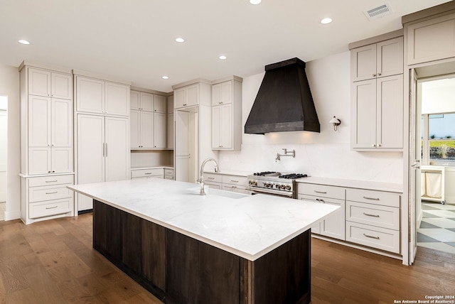 kitchen featuring sink, a spacious island, dark hardwood / wood-style flooring, stainless steel stove, and premium range hood