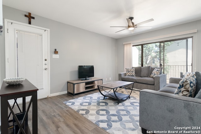 living room with ceiling fan, baseboards, and wood finished floors