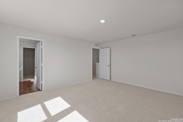 unfurnished bedroom with carpet, a spacious closet, and a closet