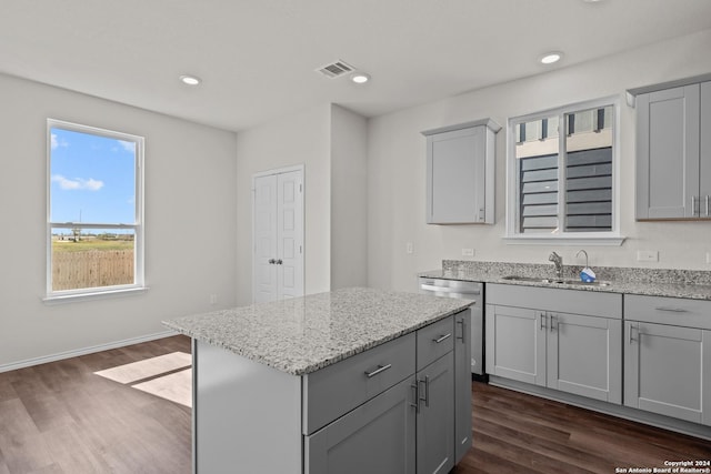 kitchen featuring a center island, sink, gray cabinets, dark hardwood / wood-style flooring, and light stone counters