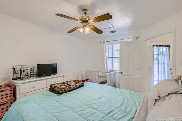 bedroom with ceiling fan and a textured ceiling