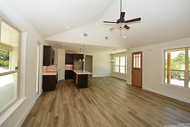 unfurnished living room with dark wood-type flooring, high vaulted ceiling, ceiling fan with notable chandelier, and sink