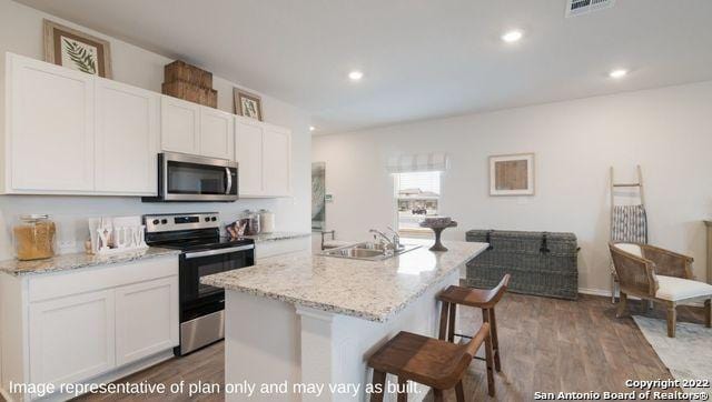 kitchen featuring appliances with stainless steel finishes, sink, white cabinets, and an island with sink