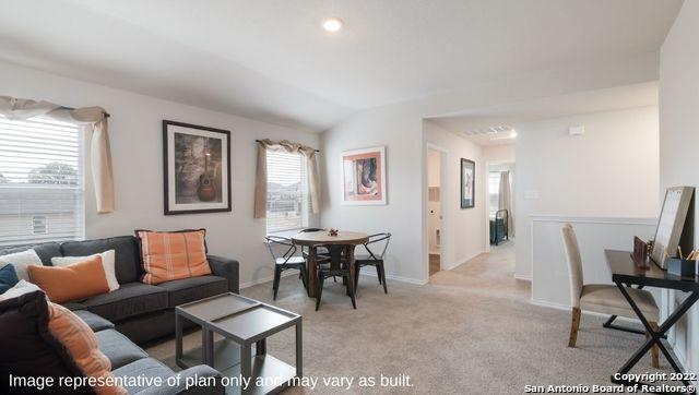 living room with light colored carpet, a healthy amount of sunlight, and vaulted ceiling