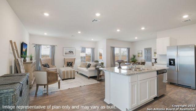 kitchen with sink, hardwood / wood-style flooring, a kitchen island with sink, stainless steel appliances, and white cabinets