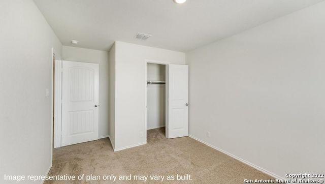 unfurnished bedroom featuring light colored carpet and a closet