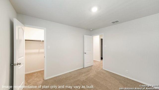 unfurnished bedroom featuring baseboards, visible vents, a spacious closet, carpet flooring, and a closet