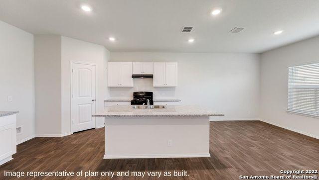 kitchen with dark wood-style floors, visible vents, white cabinetry, an island with sink, and range