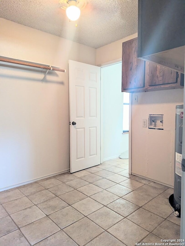 interior space with light tile patterned floors, a textured ceiling, and electric water heater