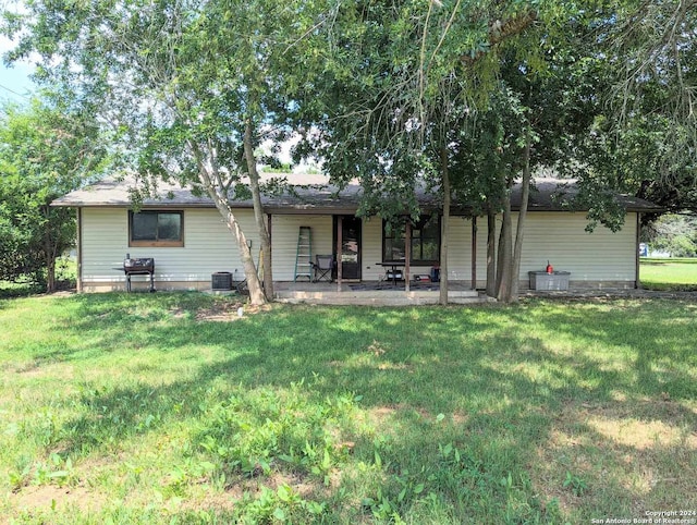 rear view of house featuring a lawn, central air condition unit, and a patio