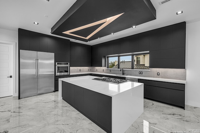 kitchen with tasteful backsplash, a large island, sink, and appliances with stainless steel finishes